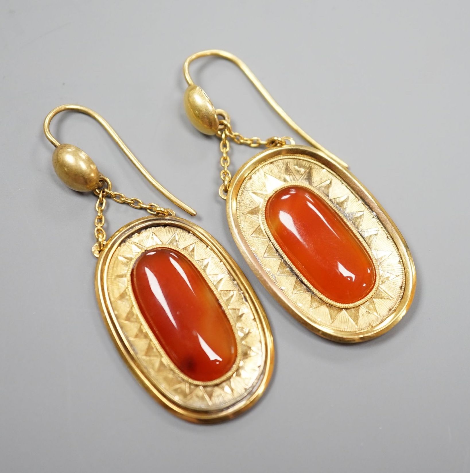 A pair of yellow metal and orange agate set oval drop earrings, overall 46mm, gross 6.8 grams.